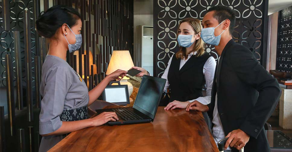 Três pessoas usando máscara na recepção representam as vantagens da terceirização de serviços especializados